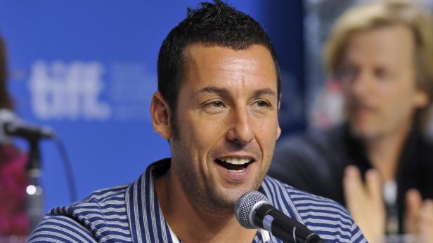 Adam Sandler lächelt in ein Mikrofon.