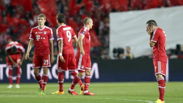 Ein enttäuschter Fußballspieler verdeckt sein Gesicht, während andere Spieler im Hintergrund stehen.