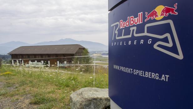Ein Schild mit dem Red Bull Ring Logo vor einer ländlichen Szene in Spielberg, Österreich.