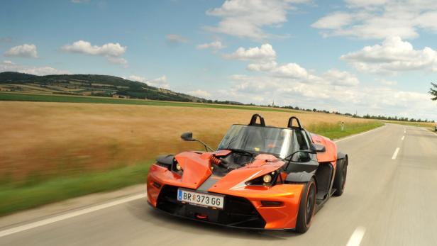 Ein orangefarbener KTM X-Bow fährt auf einer Landstraße.