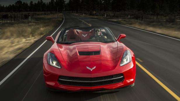 Ein rotes Corvette-Cabriolet fährt auf einer Landstraße.