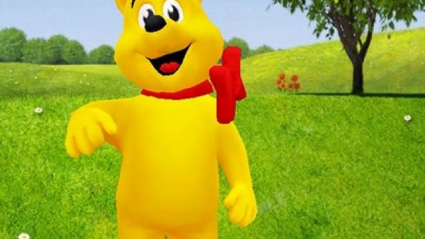 Ein gelber Haribo Goldbär steht auf einer grünen Wiese.