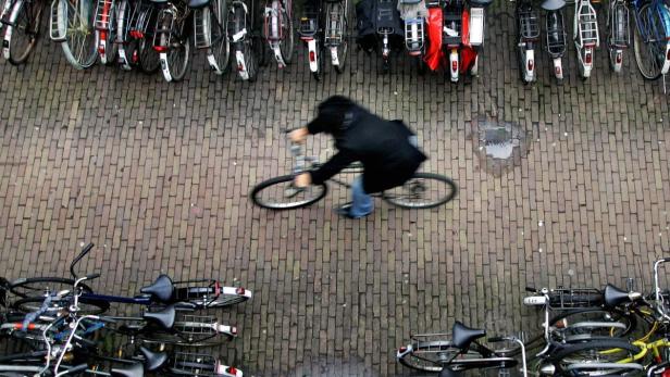 A man rides his bike in a bicycle shed near Central Station Amsterdam January 17, 2007. There are more bicycles than people in the Netherlands, where each resident clocks up an average of 917 km (573 miles) a year on two wheels. Flat as a pancake and densely populated, the Netherlands has tried to mitigate traffic congestion by encouraging its 16 million people to travel on their 18 million bikes. Amsterdam&#039;s central station has a multi-storey parking house for bikes and there are racks on every street corner. Picture taken January 17, 2007. To match story WITNESS-BICYCLES/ REUTERS/Koen van Weel (NETHERLANDS)