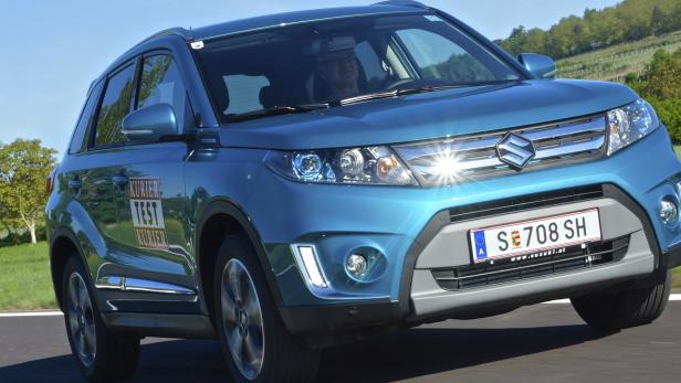 Ein türkisfarbener Suzuki Vitara fährt auf einer Landstraße.