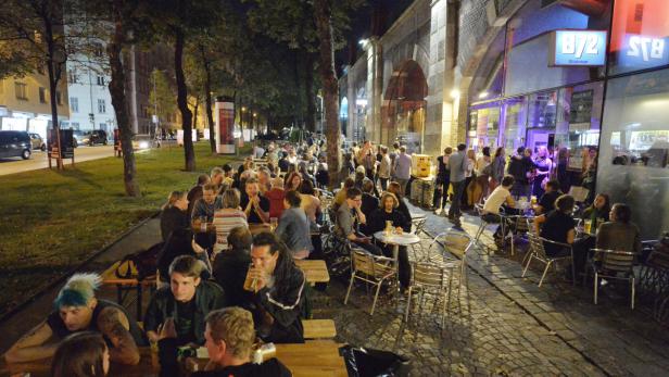 Viele Menschen sitzen abends vor dem B72 in Wien und trinken etwas.