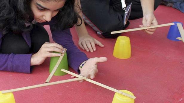 Kinder bauen eine Konstruktion mit Bechern und Holzstäben.