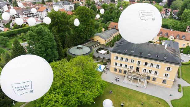 Luftaufnahme eines Schlosses mit weißen Ballons, die Botschaften zum Umweltschutz tragen.