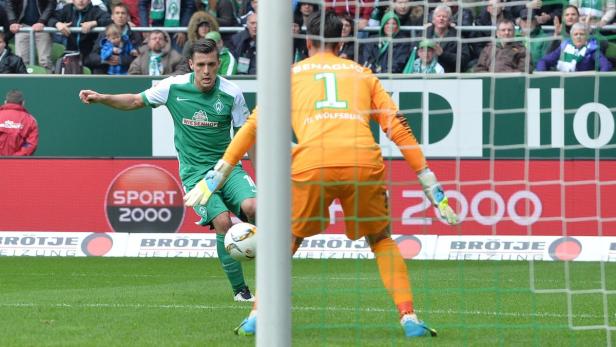 Ein Fußballspieler von Werder Bremen schießt auf das Tor, gehütet von Torwart Benaglio vom VfL Wolfsburg.