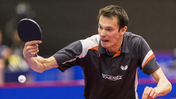 Ein Tischtennisspieler schlägt den Ball mit seinem Schläger.