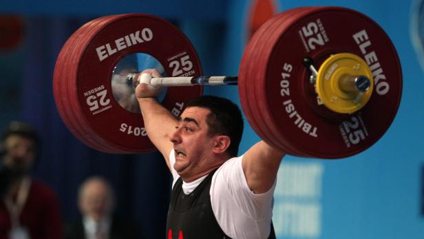 Ein Gewichtheber stemmt eine schwere Hantel über seinem Kopf.