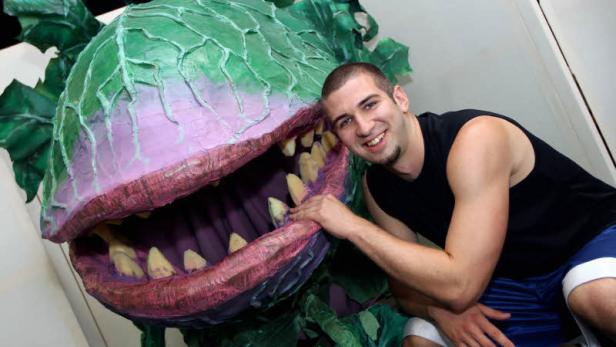 Ein Mann posiert neben einer großen, zahnreichen Pflanze, die an „Der kleine Horrorladen“ erinnert.
