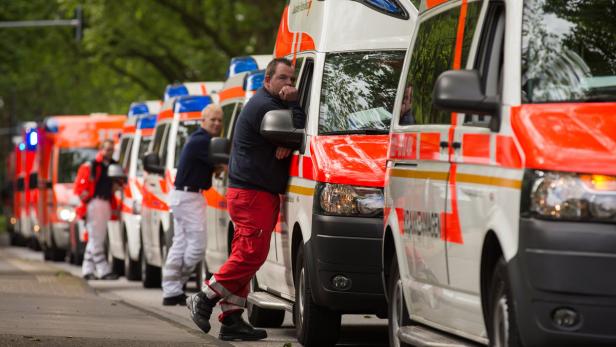 Eine Reihe von Rettungswagen steht am Straßenrand, Sanitäter sind zu sehen.