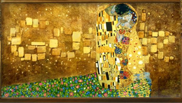 Das Gemälde „Der Kuss“ von Gustav Klimt zeigt ein Paar in goldenen Gewändern vor einem goldenen Hintergrund mit Blumenwiese.