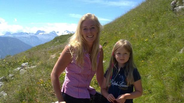 Eine Frau und ein Mädchen posieren vor einer Berglandschaft.