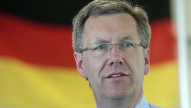 Ein Mann mit Brille steht vor einer Deutschlandflagge.