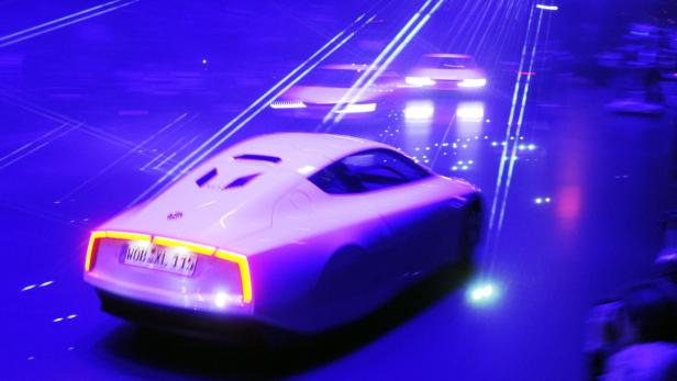 Ein weißer Volkswagen XL1 unter blauem Neonlicht.