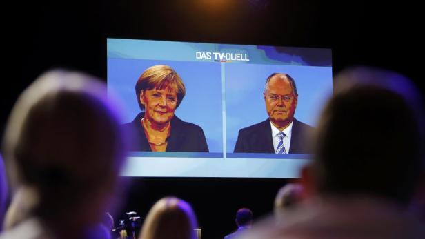 People watch German Chancellor Angela Merkel of the Christian Democratic Union (CDU) during a TV duel with her challenger, the top candidate of the Social Democratic Party (SPD) in the upcoming German general elections Peer Steinbrueck, in Berlin, September 1, 2013. German voters will take to the polls in a general election on September 22. REUTERS/Fabrizio Bensch (GERMANY - Tags: POLITICS ELECTIONS)