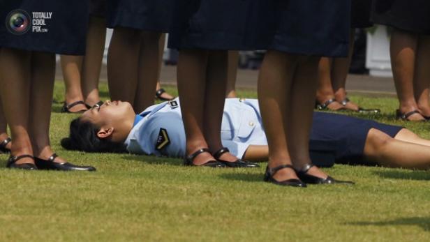 Eine Soldatin liegt während einer Parade auf dem Rasen.