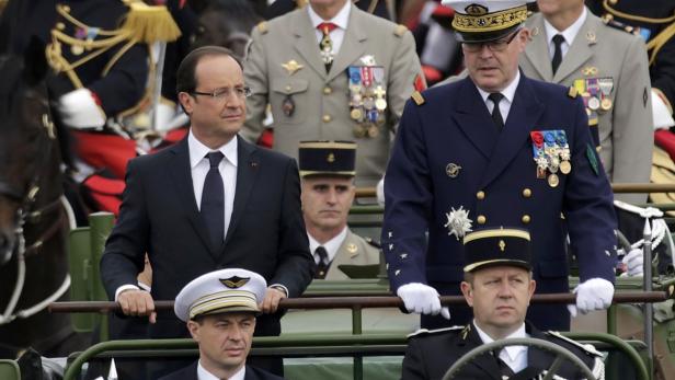 François Hollande bei einer Militärparade in Begleitung von Militärangehörigen.