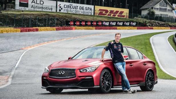 Sebastian Vettel posiert an der Rennstrecke von Spa-Francorchamps an einem roten Infiniti-Auto.
