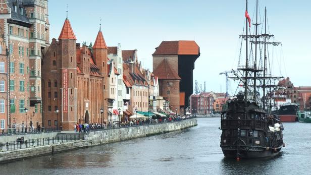 Ein Segelschiff fährt auf der Mottlau in Danzig entlang der historischen Gebäude.