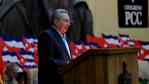 Raúl Castro hält eine Rede vor kubanischen Flaggen und einem Banner des PCC.