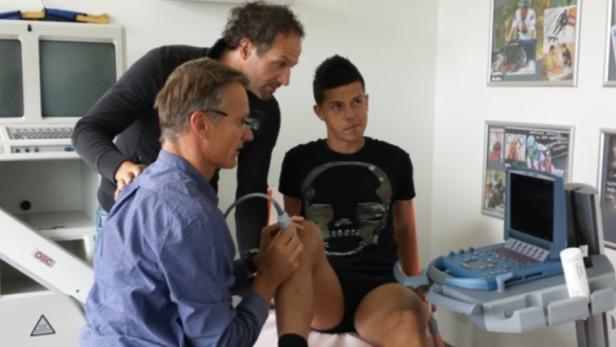 Ein Arzt untersucht das Knie eines Patienten mit Ultraschall.
