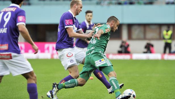 Zwei Fußballspieler kämpfen um den Ball auf dem Spielfeld.