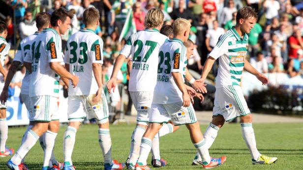 Mehrere Fußballspieler von Rapid Wien laufen über den Rasen.