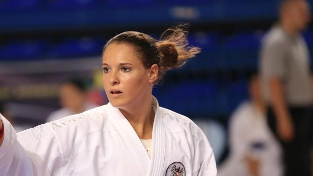 Eine Karatekämpferin im weißen Gi mit österreichischem Wappen.