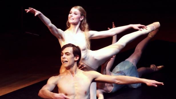 Eine Ballettaufführung mit Tänzern in Bewegung auf einer dunklen Bühne.