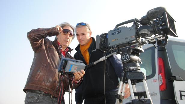 Zwei Männer arbeiten mit einer professionellen Filmkamera im Freien.