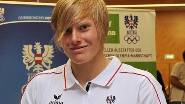Eine blonde Frau im österreichischen Olympia-Trikot lächelt.