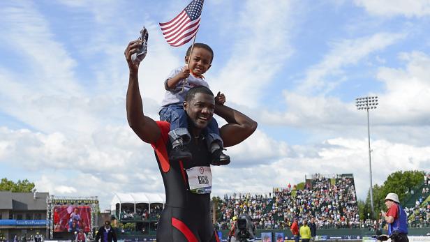 Justin Gatlin feiert mit seinem Sohn auf den Schultern und einer US-Flagge in der Hand.