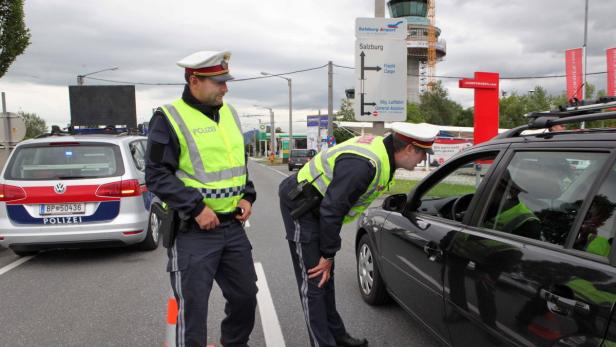 Zwei Polizisten kontrollieren ein Auto in der Nähe des Salzburger Flughafens.
