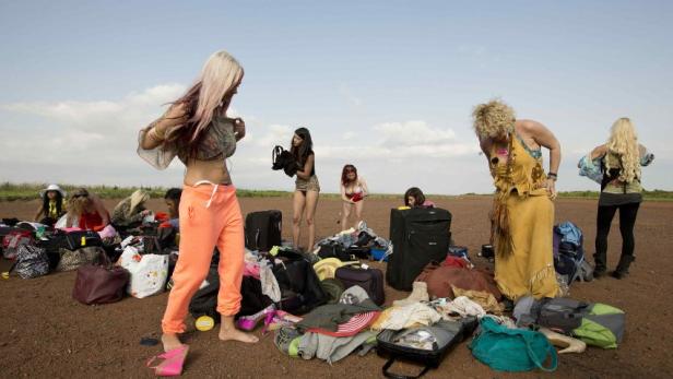 Eine Gruppe von Frauen steht inmitten von Koffern und Gepäckstücken auf einem Feld.