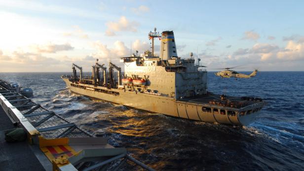 Ein Versorgungsschiff der Marine wird von einem Hubschrauber angeflogen.