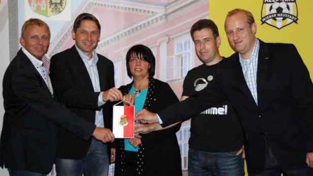 Eine Gruppe von Personen hält eine kleine Flagge von Wiener Neustadt.