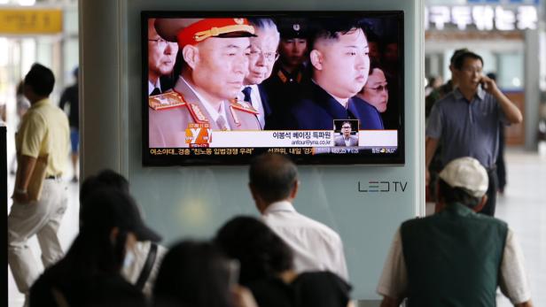 Menschen beobachten im öffentlichen Raum eine Nachrichtensendung über Kim Jong-un.