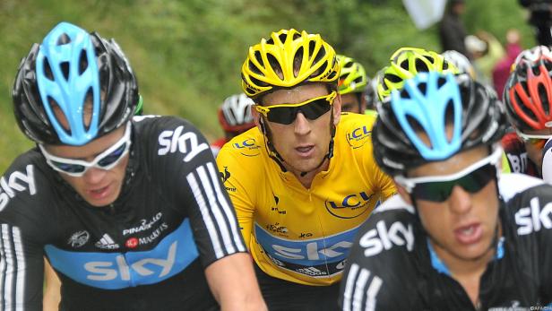 Radfahrer in gelbem Trikot, umgeben von anderen Fahrern des Team Sky.