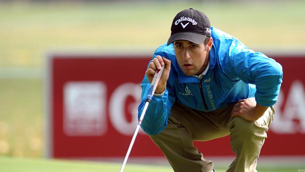 Ein Golfspieler zielt mit seinem Putter auf dem Grün.