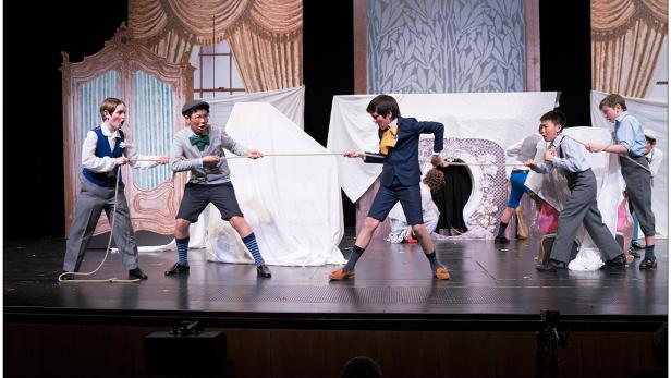 Eine Gruppe von Jungen zieht auf einer Bühne an einem Seil.