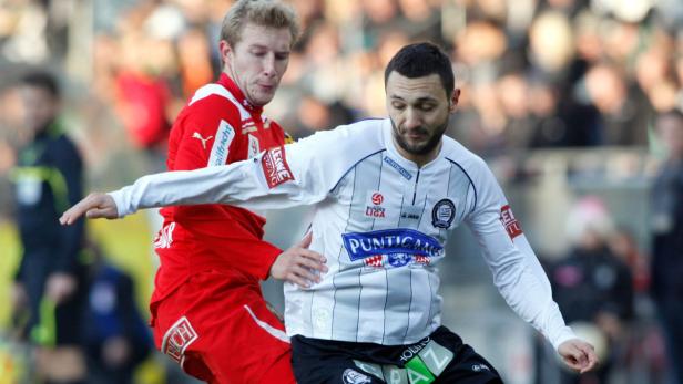 Zwei Fußballspieler kämpfen um den Ball während eines Spiels.