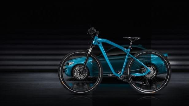 Ein blaues BMW-Fahrrad steht vor einem passenden BMW-Auto.