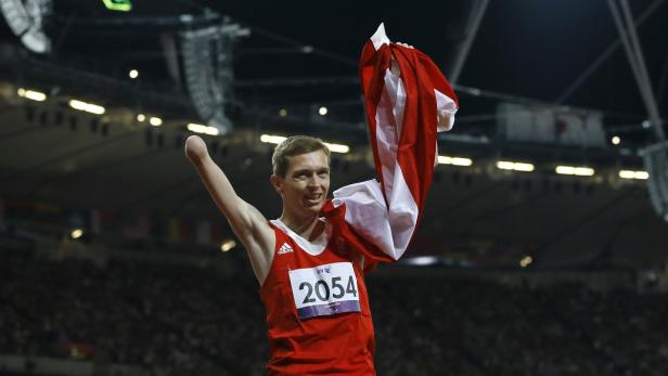Ein behinderter Athlet feiert mit einer rot-weißen Flagge in einem Stadion.