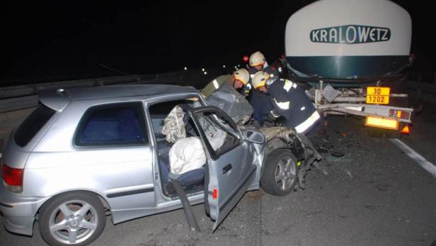 Ein silberner Kleinwagen ist in einen Tanklastwagen der Marke Kralowetz verunglückt; Feuerwehrleute sind vor Ort.