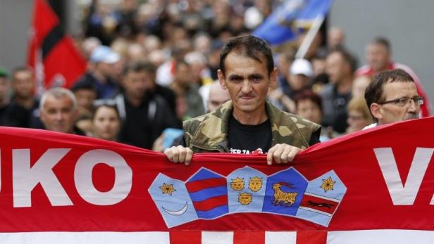 A man carries a Croatian flag during a protest against signs in Serb Cyrillic script placed in the city of Vukovar September 3, 2013. Several hundred Croat protesters tore down the signs that were put up on Monday in the Croatian city devastated during the independence war with Serb-dominated Yugoslavia, state radio said. The signs were put up in Vukovar in line with a law in the newest European Union member that makes bilingual signs mandatory in any area where more than one third of the local population belongs to an ethnic minority group. Vukovar was reduced to rubble during a three-month siege by Yugoslav and Serbian forces in late 1991. Though rebuilt, the town remains poor, with high unemployment and ethnic tensions. REUTERS/Antonio Bronic (CROATIA - Tags: CIVIL UNREST POLITICS SOCIETY)