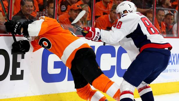 Zwei Eishockeyspieler kämpfen an der Bande um den Puck.