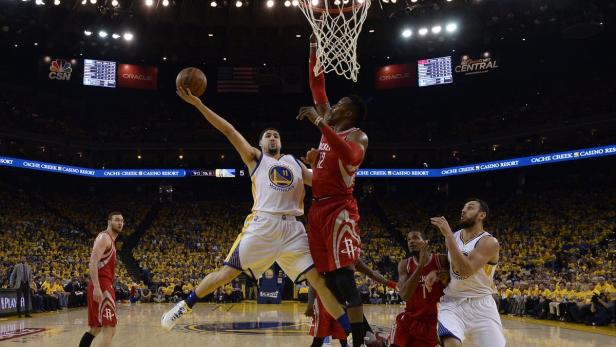 Ein Basketballspieler der Golden State Warriors wirft den Ball auf den Korb, während ein Spieler der Houston Rockets ihn verteidigt.