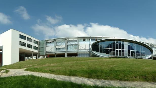 Ein modernes, architektonisch interessantes Gebäude auf einer grünen Anhöhe.